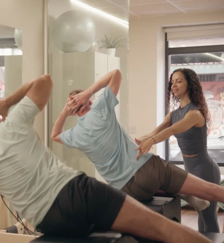 Instructoras de Siamo Pilates Madrid guiando a alumno senior en ejercicio personalizado