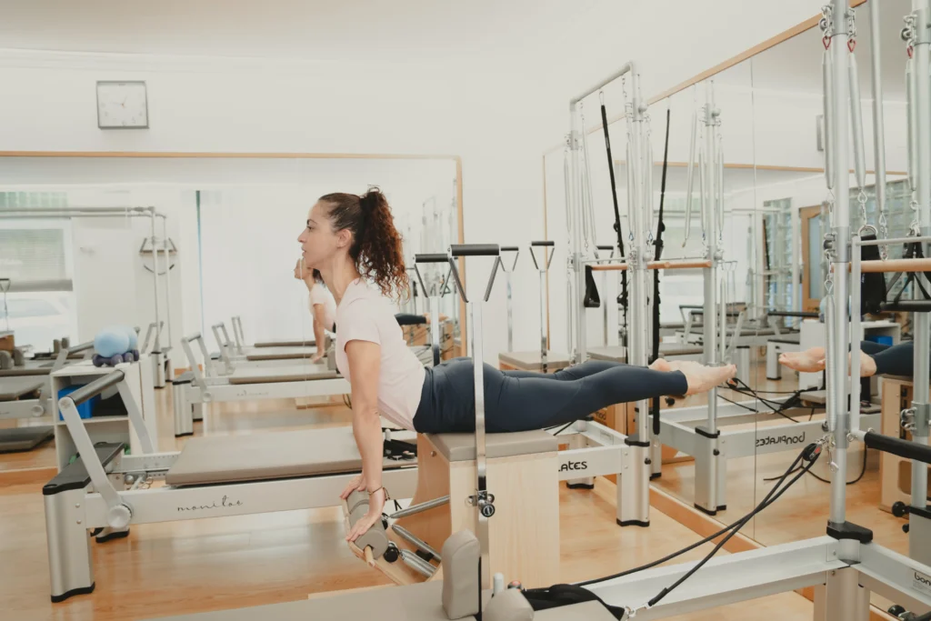 Mujer practicando ejercicio de extensión en reformer en estudio de pilates en Madrid