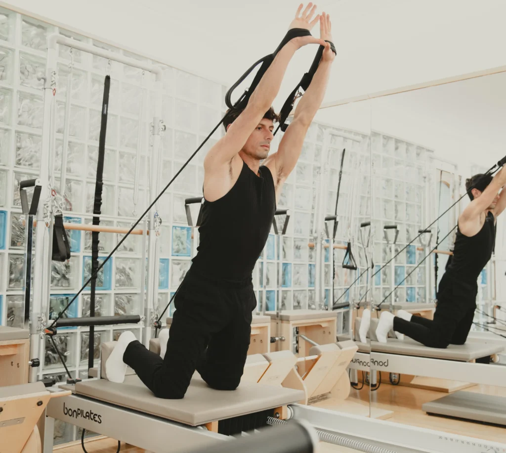 Ejercicio dinámico con correas en máquina reformer por alumno en clase de pilates en Siamo Madrid
