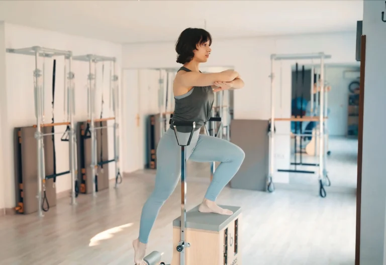 Mujer realizando ejercicio en silla de pilates en un estudio moderno.