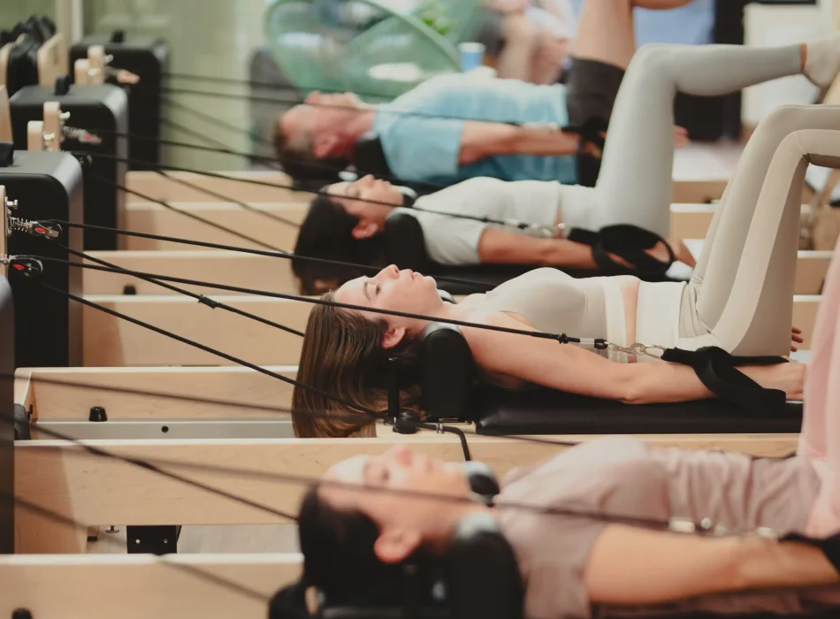 Clase grupal en máquinas reformer – Pilates en Madrid Alumnos practicando pilates en máquinas reformer en grupo en Siamo Pilates Madrid